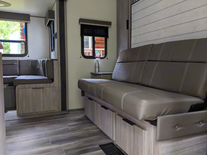 Cozy RV rental interior showing a gray sofa, dinette, and light wood-grain cabinetry.. Keystone RV Passport SL 2021