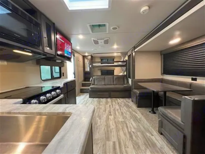 Spacious RV rental interior featuring a modern kitchen, dining area, and bunk beds, perfect for family adventures.. Grand Design Transcend Xplor 265BH 2021