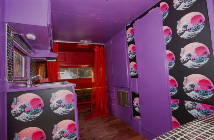 Step into this unique purple & red vaporwave RV rental interior. Features a kitchen, artistic wave panels, and eclectic decor.. Kit Kit Trailer Deluxe 1978