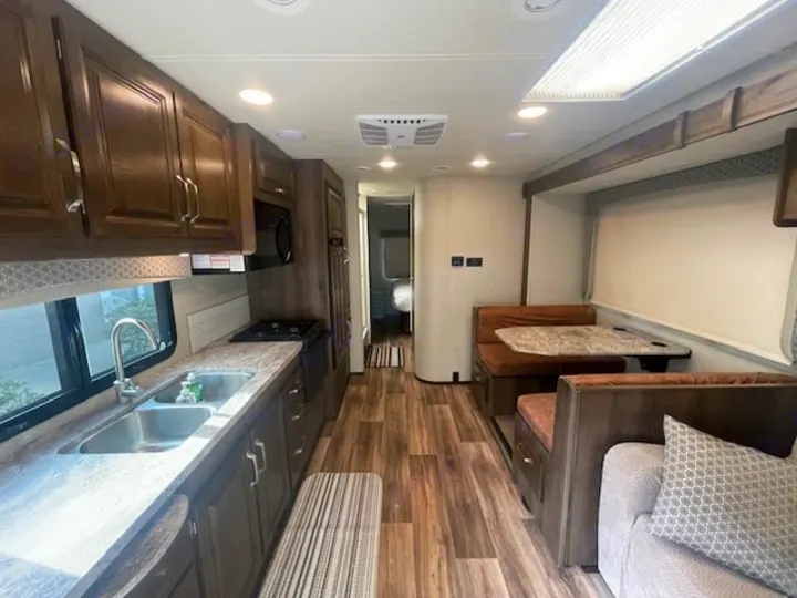 A modern RV rental interior features a full kitchen, dinette, and cozy living space, ready for your next adventure.. Jayco Greyhawk 2019