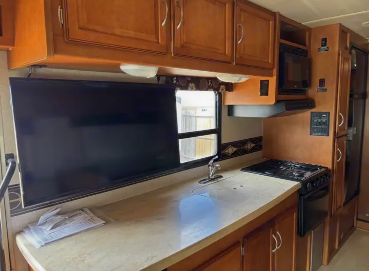 This RV rental's cozy kitchen features wooden cabinets, a TV, sink, stove, microwave, and fridge for your travels.. Winnebago Minnie Winnie 2015