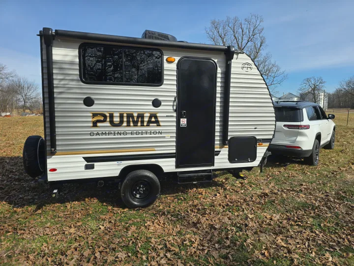 A white SUV tows a Puma Camping Edition RV, perfect for your next rv rental adventure.. Palomino Puma Camping Edition 122BHCE 2026