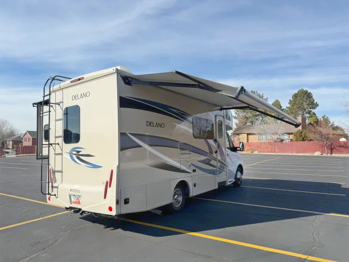 Beige Delano RV rental with an extended awning, parked in a sunny lot, ready for your next adventure.. Thor Delano 2021