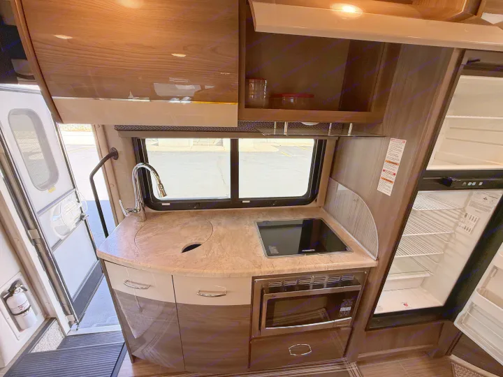 This RV rental features a well-equipped compact kitchen: sink, Dometic cooktop, microwave, and open refrigerator.. Thor Delano 2021