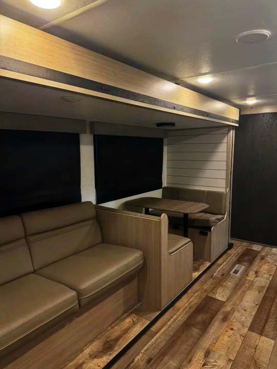Modern rv rental living area: sofa, dinette, and light wood decor. Great for comfortable travel.. Crossroads RV Sunset Trail Sport 2025