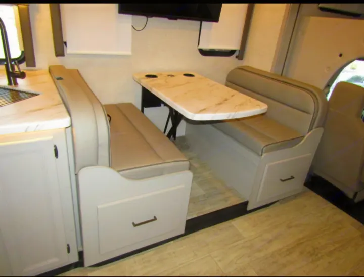 This RV rental features a cozy dinette with booth seating, under-seat storage, and a convenient kitchen counter.. Thor Chateau 2024