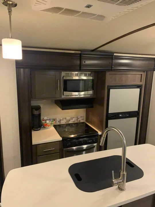 Modern RV rental kitchen with microwave, stove, fridge, sink, and coffee maker. Perfect for comfortable road trips.. Crossroads RV Sunset Trail Super Lite 2018