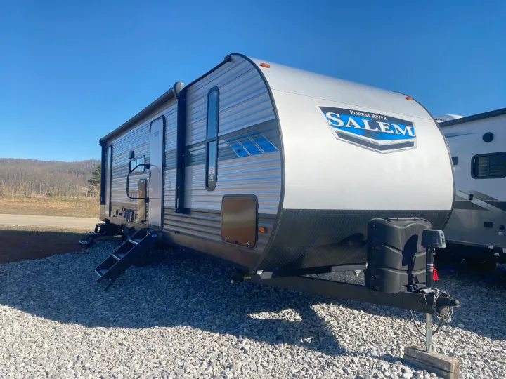 This Forest River Salem travel trailer, ready for an rv rental, gleams under a blue sky on a gravel lot. Your adventure awaits!. Forest River Salem 2022