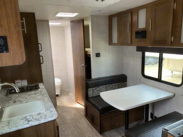 This RV rental interior features a kitchen sink, dinette, and bathroom, designed for comfortable travel.. Gulf Stream Ameri-Lite Super Lite 2022