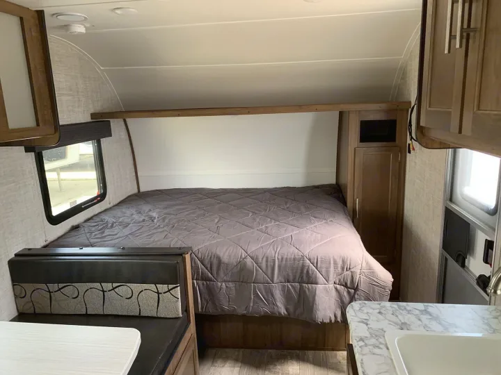 rv rental: Interior view with a grey comforter on the bed, nearby dinette seat, and glimpse of the kitchen sink.. Gulf Stream Ameri-Lite Super Lite 2022