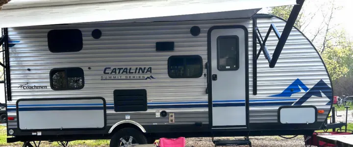 This Catalina Summit Series travel trailer, a great option for your next rv rental, features a gray and blue exterior with an extended awning.. Coachmen Catalina Summit 2021