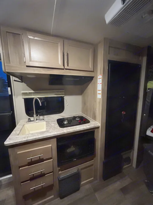 RV rental kitchen interior featuring a sink, stovetop, microwave, and refrigerator.. Coachmen Catalina Summit 2021