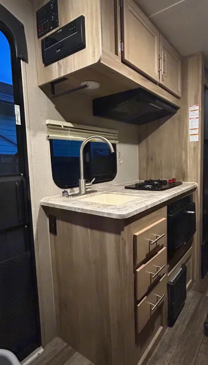 This rv rental kitchen offers a sink, stove, microwave, overhead cabinets, and an entertainment system.. Coachmen Catalina Summit 2021