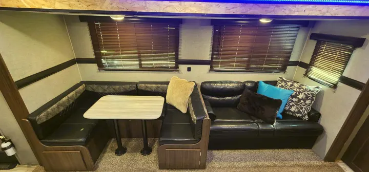 Spacious RV rental interior featuring a comfortable dinette with U-shaped seating, a separate sofa, and blinds.. Crossroads RV Zinger 2019