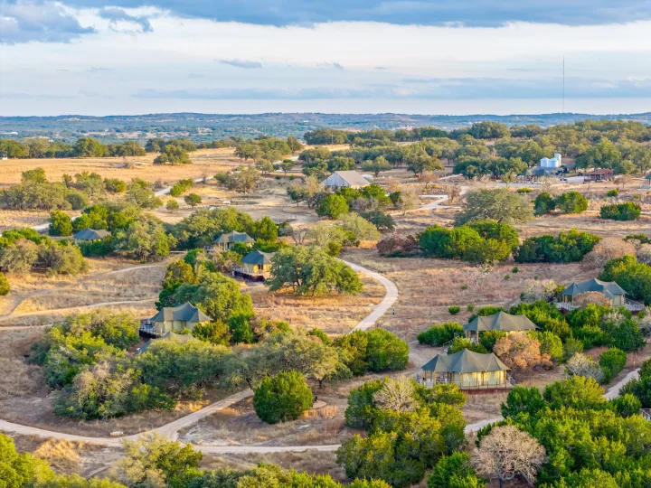 Elevated view: Glamping safari tents and winding roads in a scenic, arid landscape. A unique escape alternative to an RV rental trip.