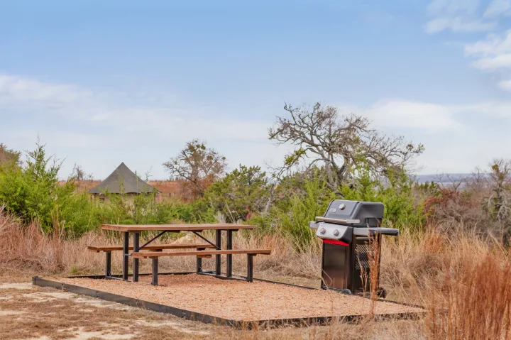 RV rental ready for your adventure! Enjoy a picnic table and grill on a gravel pad, with a glamping tent nearby in nature.