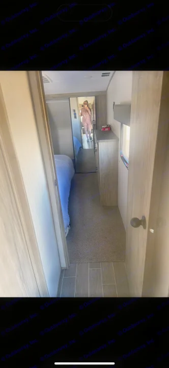 RV rental bedroom view. A mirror reflects a person in a patterned outfit. Shows a bed, dresser, and tiled/carpeted floor.. Forest River Cherokee Arctic Wolf 2020