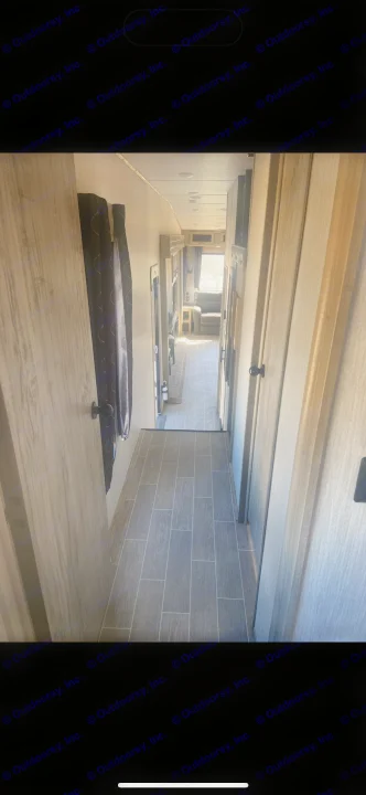 Explore this modern RV rental's interior hallway, featuring sleek wood-look tile and natural light towards the living area.. Forest River Cherokee Arctic Wolf 2020