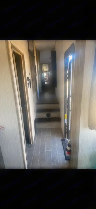 RV rental: Modern interior hallway with stairs, open door, and fire extinguisher. Person reflected in mirror.. Forest River Cherokee Arctic Wolf 2020