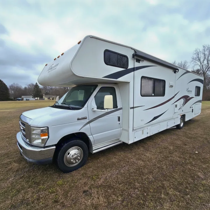 White Class C motorhome RV rental, parked on dry grass. Features an awning & graphics, ready for your next adventure.. Coachmen Freelander 2011