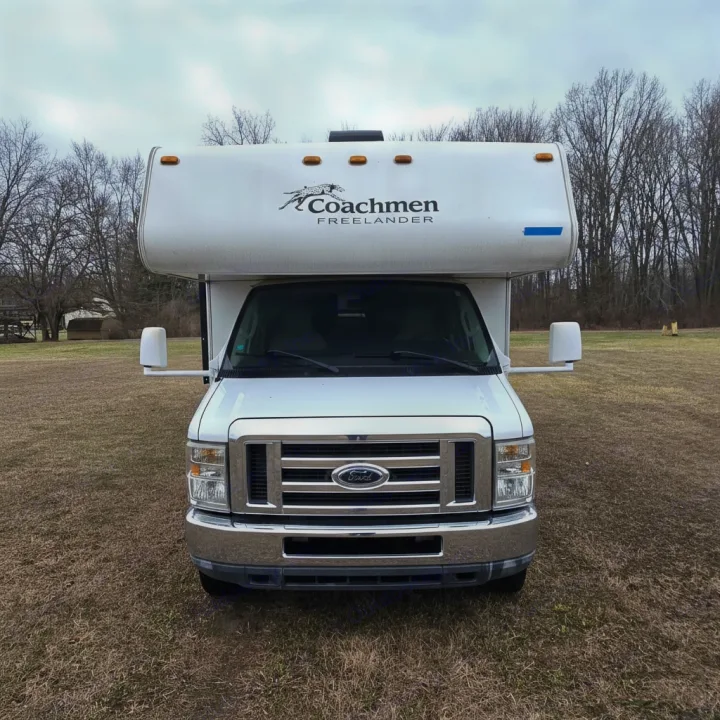 Front view of a white Coachmen Freelander RV rental parked on a brown grassy field under an overcast sky.. Coachmen Freelander 2011