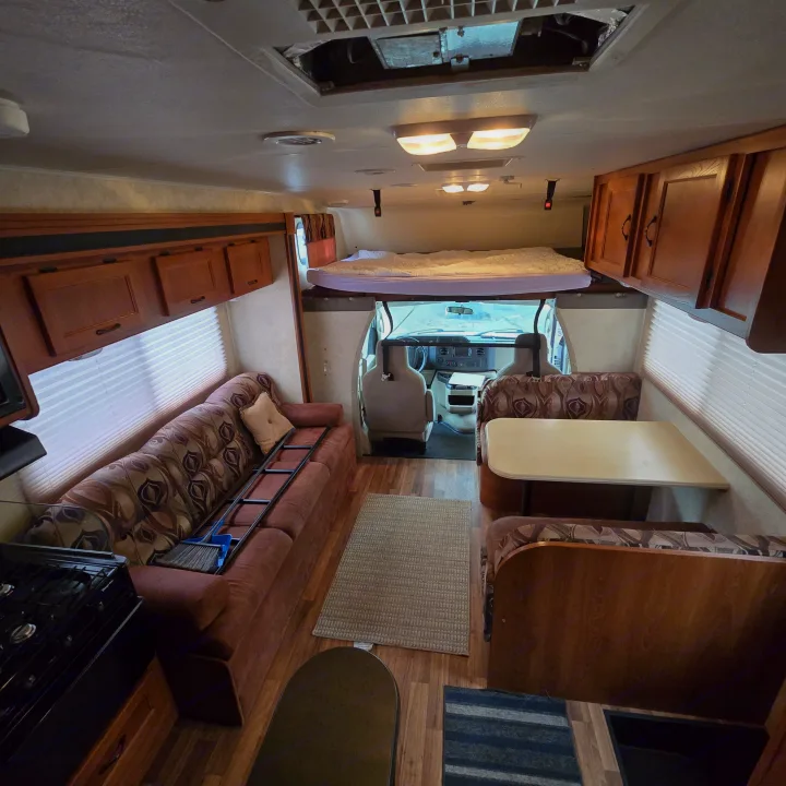 Step into this RV rental! Features a living room, dining area, kitchen stove, and an overhead bed.. Coachmen Freelander 2011