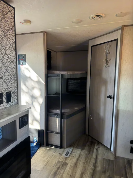 RV rental interior featuring bunk beds, a control panel, a closet door with hooks, and a smoke detector on the ceiling.. Coleman Lantern 2022