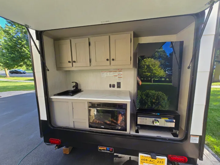 This RV rental shows a compact outdoor kitchen with a sink, microwave, fridge, and grill.. Clipper 3K 2025