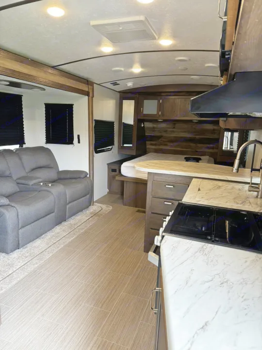 Modern RV rental interior with kitchen, recliner sofa living space, and a compact bedroom. Perfect for comfortable journeys.. Keystone RV Passport Grand Touring 2019