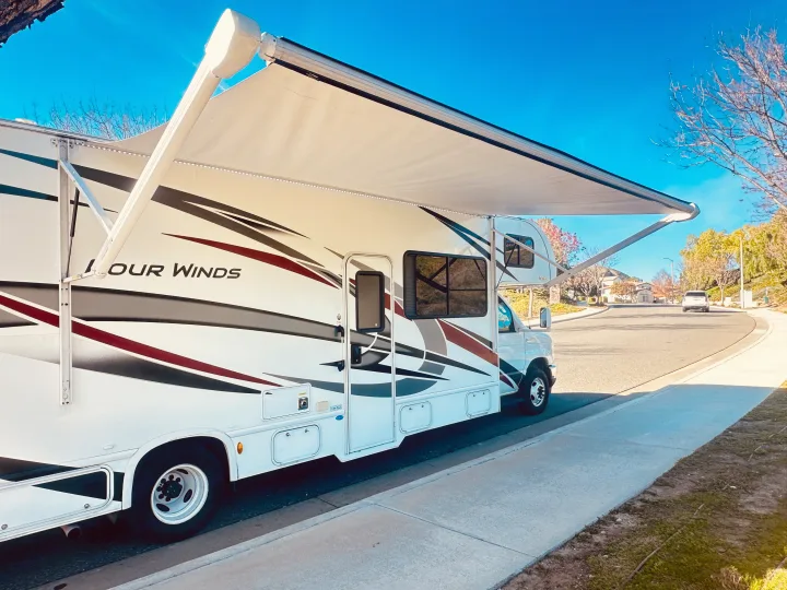 Modern Four Winds RV rental with extended awning & LED lights, ready for your next outdoor escape on a sunny day.. Thor Four Winds 2022