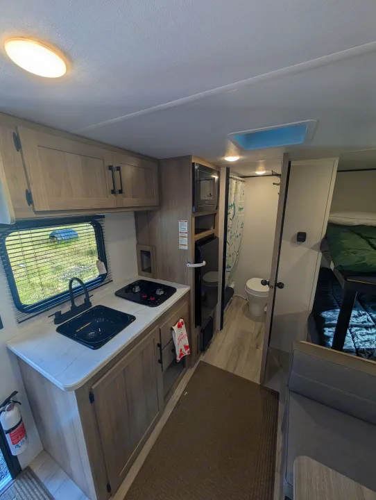 Cozy rv rental interior showcasing a compact kitchen, bathroom, and bunk beds, ideal for travel and adventure.. Keystone RV Coleman 2025