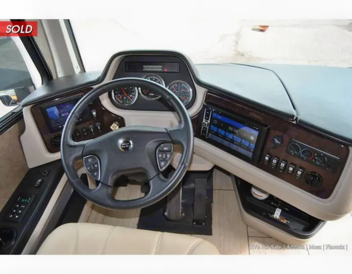 RV rental driver's cockpit featuring a sleek dashboard, steering wheel controls, and large infotainment screen for navigation.. Holiday Rambler Endeavor 2018