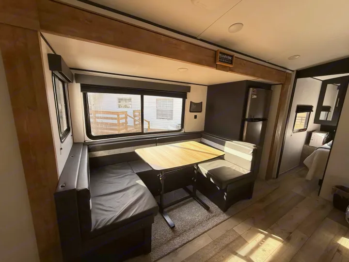 Experience comfort in this modern RV rental dinette, featuring a U-shaped booth, table, and natural light from large windows.. Keystone RV Springdale 2022