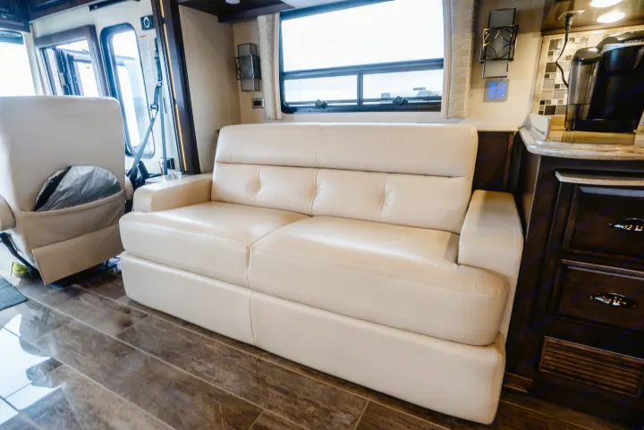 Experience an RV rental: plush cream sofa, wood-style flooring, and kitchen amenities in a modern motorhome interior.. Dutch Star Dutch Star Motorhome 2018