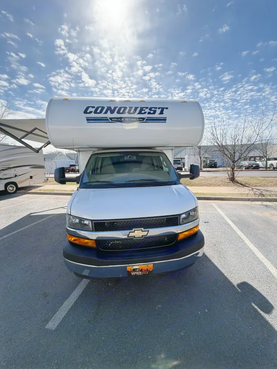 Front view of a white Gulf Stream Conquest Class C RV rental, parked on a sunny day with scattered clouds.. Gulf Stream Conquest 2024