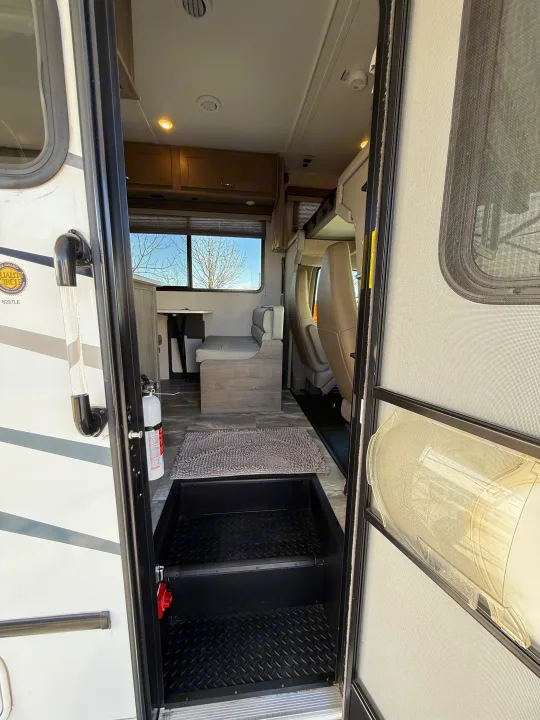 RV rental interior: Steps lead to a cozy dinette, seating, and overhead storage. Fire extinguisher by the door.. Gulf Stream Conquest 2024