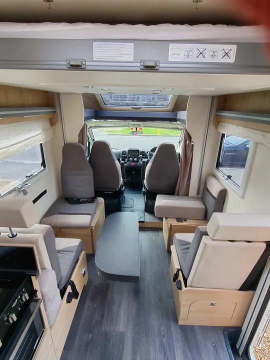 Spacious RV rental interior: dining area, driver's cabin, and overhead bed with clear safety warnings.. Chausson 720 VIP Titanium 2021