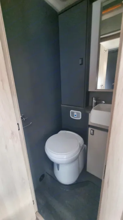 Compact RV rental bathroom showcasing a toilet, sink, mirror, and modern gray cabinetry for comfortable travel.. Auto-Trail F74 2025