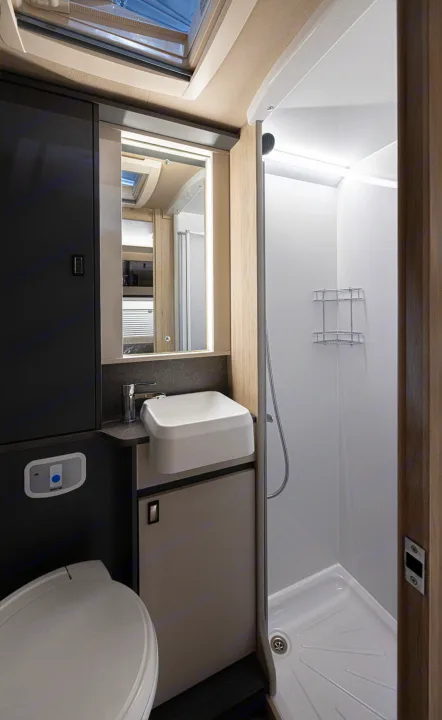 Compact RV rental bathroom with toilet, sink, lighted mirror, and shower stall, perfect for on-the-road convenience.. Auto-Trail F74 2025