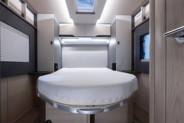 This clean, modern rv rental bedroom offers a compact bed with bright overhead lighting, ample storage, and a skylight.. Auto-Trail F74 2025