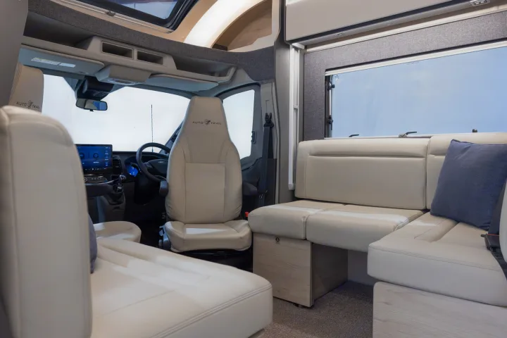 Spacious and modern RV rental interior featuring swiveling front seats, a well-equipped driver's cab, and comfortable living area seating.. Auto-Trail F70 2025