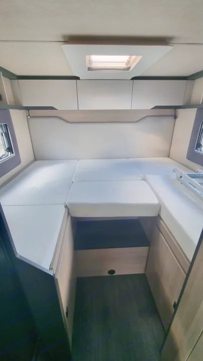 Inside a modern RV rental: a flexible sleeping area featuring white mattresses, overhead storage, side windows, and a skylight.. Auto-Trail F70 2025