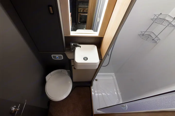 This RV rental bathroom features a white toilet on the left, a square sink with a mirror, and a shower stall on the right.. Auto-Trail F70 2025