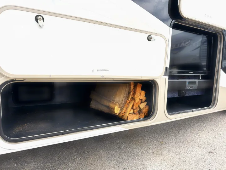 RV rental: Open external storage bays. One holds firewood, the other an outdoor TV & soundbar for entertainment.. Coachmen Leprechaun 2020