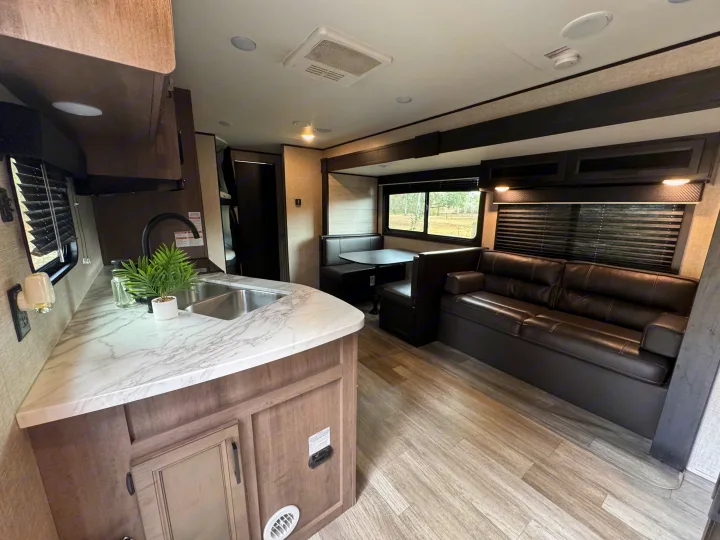 Modern RV rental interior with a kitchen counter, sink, booth dinette, and sofa for comfortable travel.. Jayco Jay Flight 2022