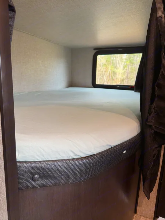 An inviting rv rental bunk bed, featuring light blue sheets and a window looking out to trees, for a comfortable stay.. Jayco Jay Flight 2022