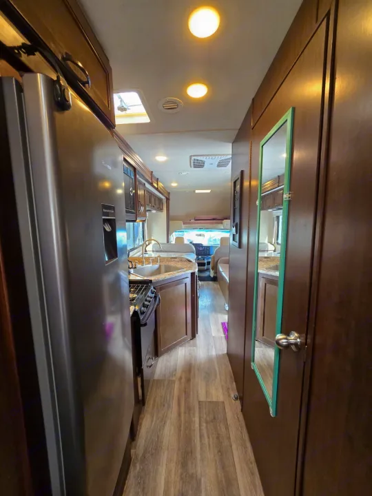 This rv rental interior features a modern kitchen, living area, and bright lighting, offering comfort for travel adventures.. Thor Four Winds 2019