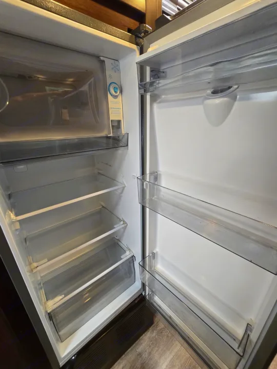 Empty RV rental refrigerator interior, showing adjustable shelves and top freezer compartment, ready for use.. Thor Four Winds 2019
