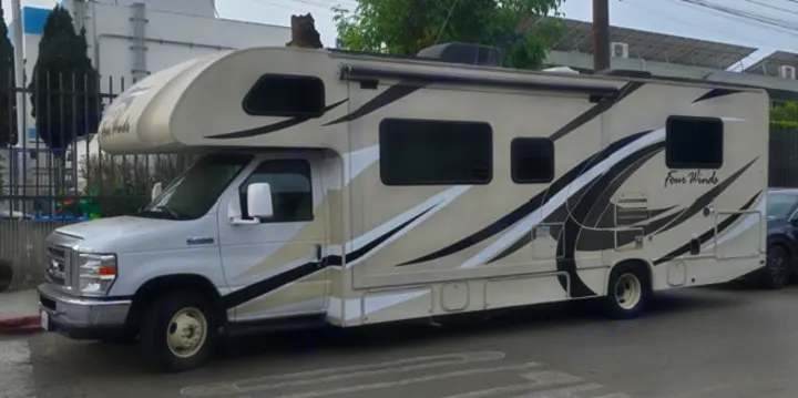 Beige and white Class C RV with black graphics, a great rv rental option for travel & camping adventures.. Thor Four Winds 2019