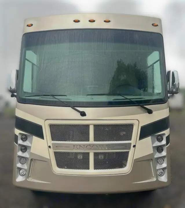 Front of a beige Encore motorhome, ideal for your RV rental. Features grille, wipers, and lights on a wet day.. Coachmen Encore 2021